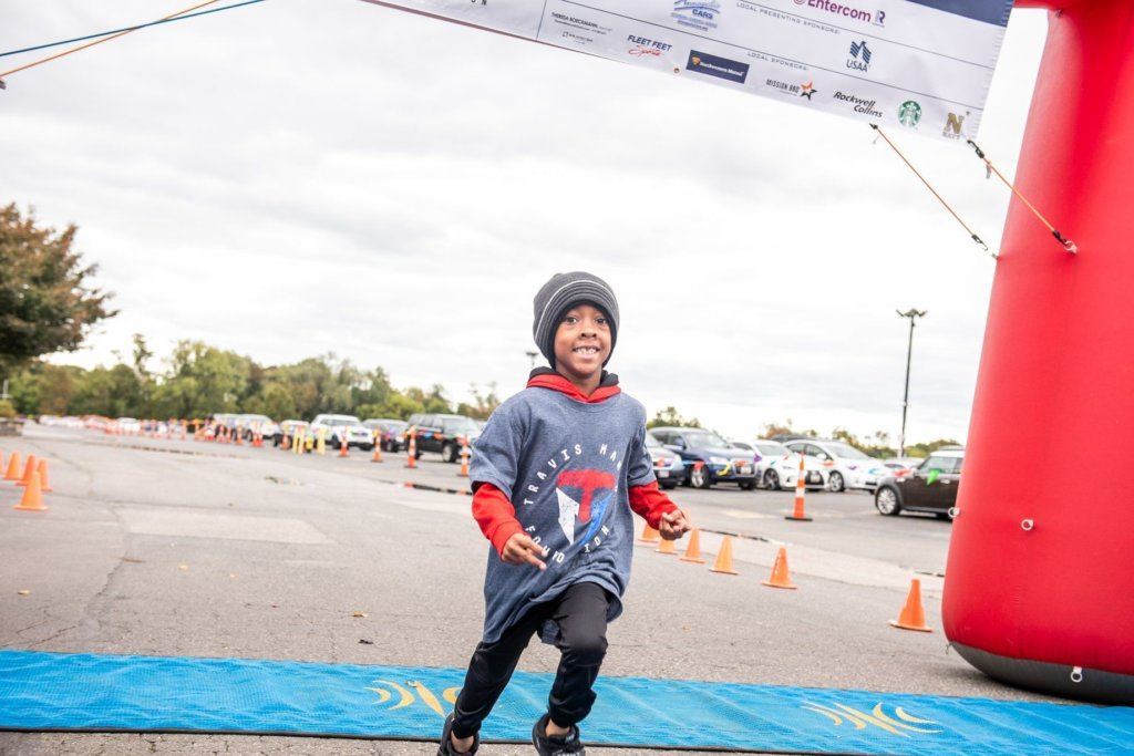 Participants get a free T-shirt. This boy finishing the 1-mile race in 2018 put his on before the race.