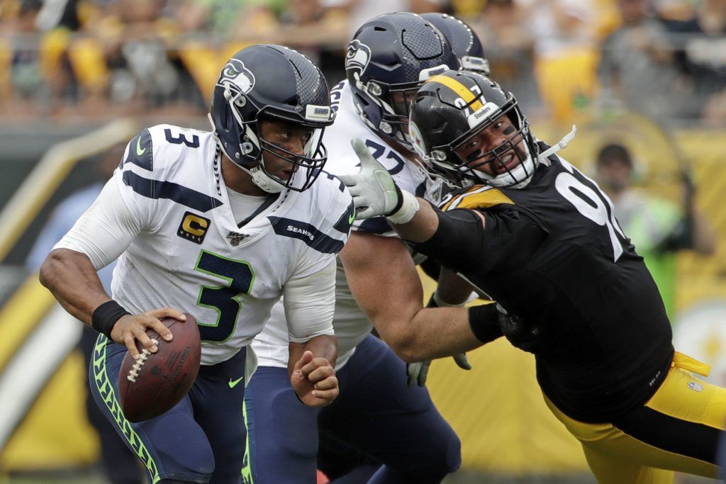 Seattle Seahawks quarterback Russell Wilson (3) scrambles past Pittsburgh Steelers defensive end Cameron Heyward (97), who is blocked by Seahawks offensive guard Ethan Pocic (77) during the second half of an NFL football game in Pittsburgh, Sunday, Sept. 15, 2019. The Seahawks won 28-26.