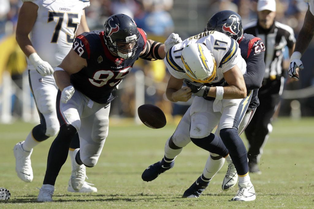 Houston Texans defensive end J.J. Watt, left, and outside linebacker Whitney Mercilus, right, force Los Angeles Chargers quarterback Philip Rivers to fumble during the second half of an NFL football game Sunday, Sept. 22, 2019, in Carson, Calif.