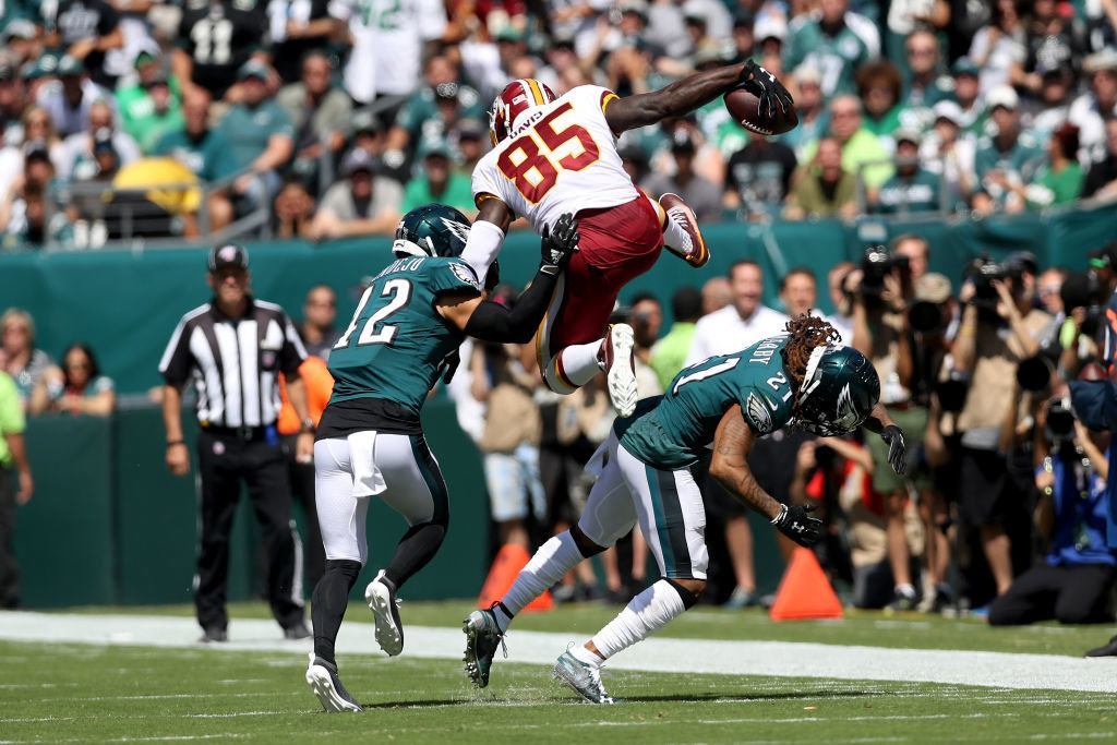Vernon Davis #85 of the Washington Redskins jumps over Andrew Sendejo #42 and Ronald Darby #21 of the Philadelphia Eagles to score a first-quarter touchdown at Lincoln Financial Field on Sept. 8, 2019 in Philadelphia, Pennsylvania.