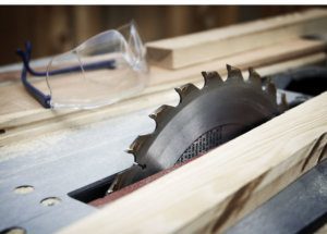 A table saw with wood and safety goggles