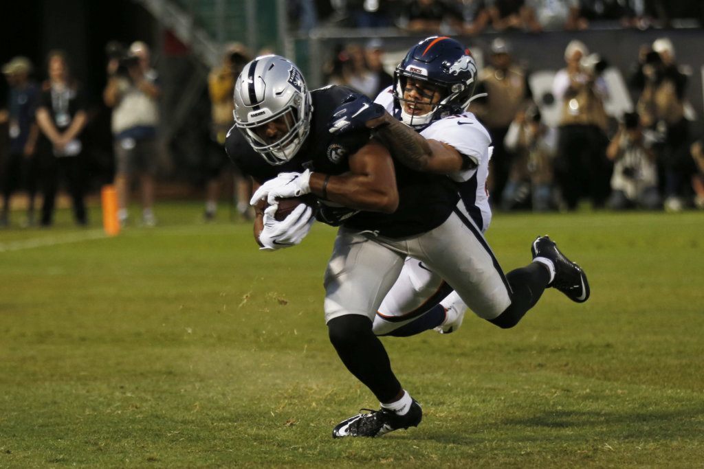 Oakland Raiders wide receiver Tyrell Williams scores a touchdown as Denver Broncos free safety Justin Simmons looks on during the first half of an NFL football game Monday, Sept. 9, 2019, in Oakland, Calif.