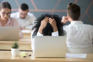 Frustrated african american woman feeling despair in shared office with laptop
