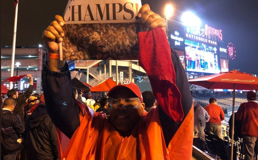 A fan holds up a newspaper heralding the Nats' World Series win.