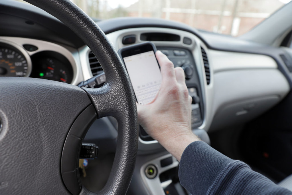 Distracted driver with phone in hand, vehicle interior