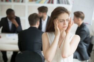 Stressed female corporate employee having migraine during briefing.