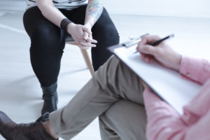 Close up on difficult teenager with tattoo during therapy with counselor