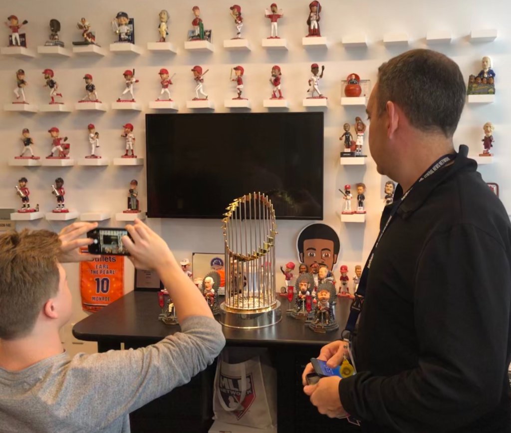 Here's the Commissioner's Trophy with WTOP's colorful Bobblehead Wall at the Sports Desk on Monday.