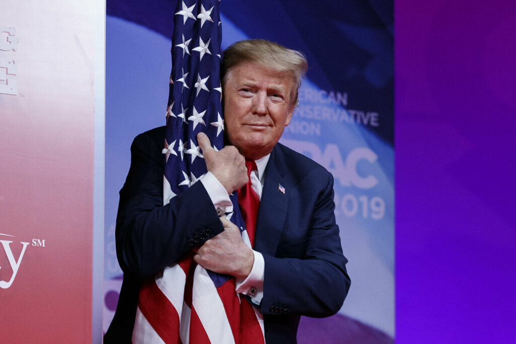 President Donald Trump hugs the American flag as he arrives to speak at the Conservative Political Action Conference, CPAC 2019, in Oxon Hill, Md., on March 2, 2019.