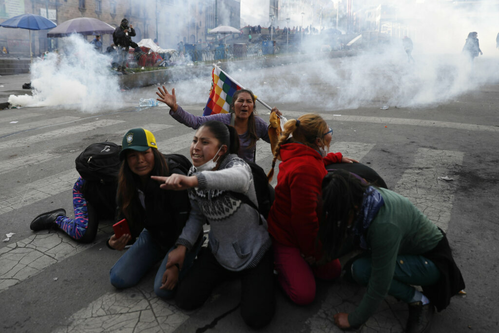 Supporters of former President Evo Morales protect themselves from tear gas launched by the police in La Paz, Bolivia, on Nov. 15, 2019.