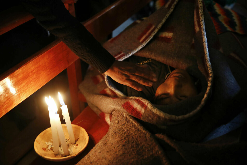 A mourner places a hand on the shoulder of Devi Posto, killed during clashes between security forces and supporters of former President Evo Morales, during a vigil at the San Francisco de Asis church in El Alto, on the outskirts of La Paz, Bolivia, on Nov. 20, 2019.