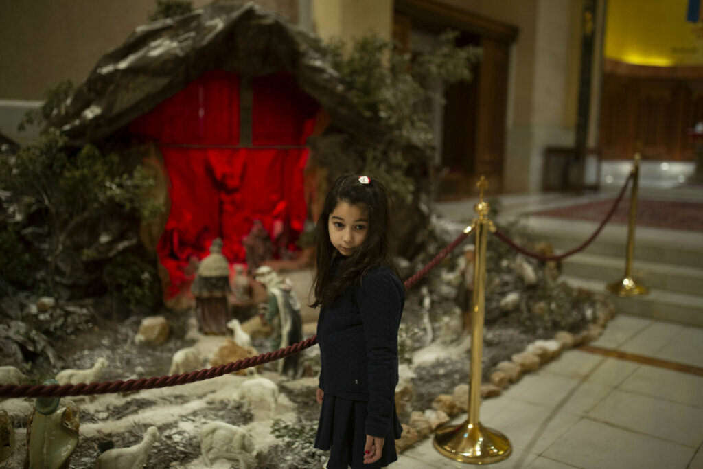 A girl stands next to a nativity scene during Christmas mass at at the Maronite Cathedral of Saint George on Wednesday, Dec. 25, 2019 in Beirut, Lebanon.