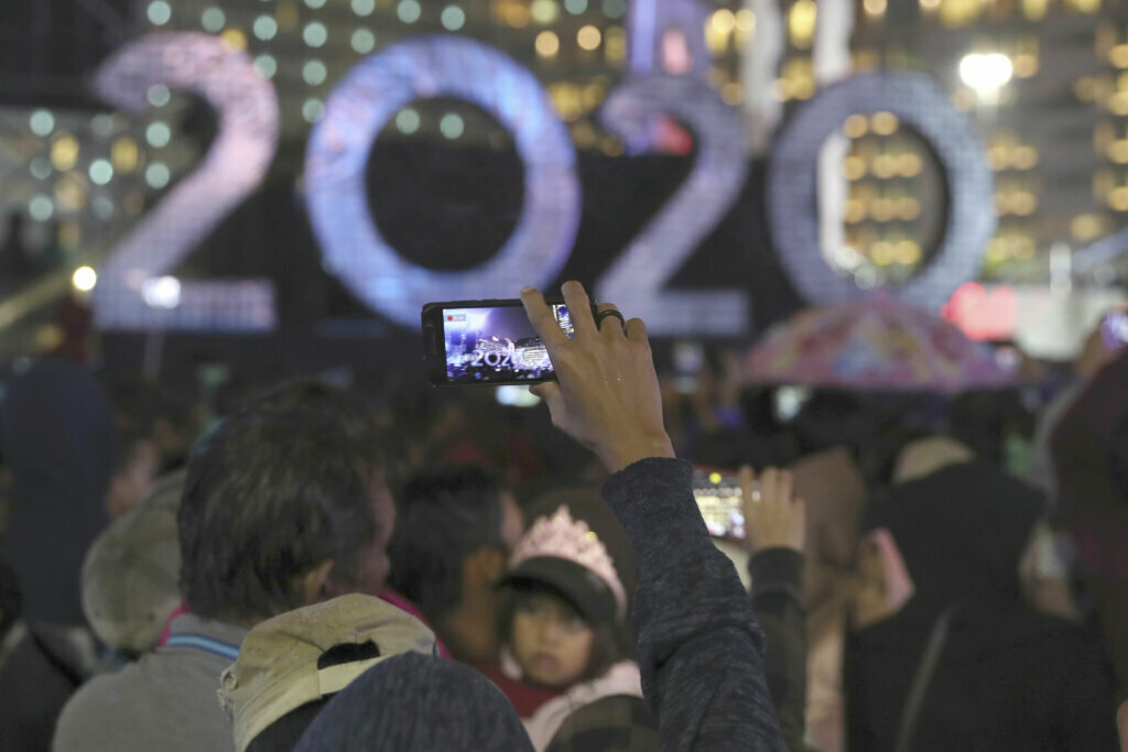 A man takes a picture near the 2020 sign board in the main business district on New Year's Eve in Jakarta, Indonesia, late Tuesday, Dec. 31, 2019. Tens of thousands of revelers in Indonesia's capital of Jakarta were soaked by torrential rains as they waited for New Year's Eve fireworks.