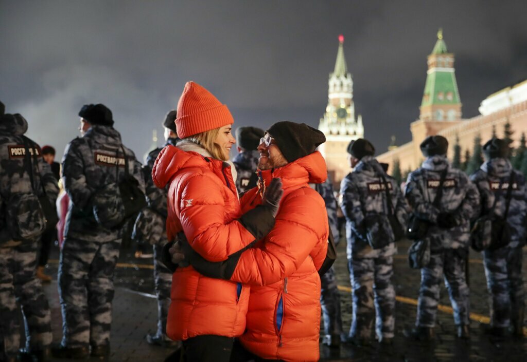A couple share a tender moment during New Year's celebrations in Red Square with the Spasskaya Tower, second right, in the background in Moscow, Russia, Wednesday, Jan. 1, 2020. Russians began the world's longest continuous New Year's Eve with fireworks and a message from President Vladimir Putin urging them to work together in the coming year.