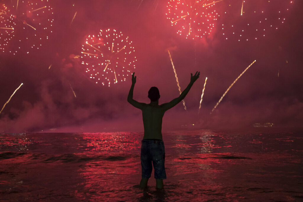A man watches fireworks exploding over Copacabana Beach during the New Year's celebrations, in Rio de Janeiro, Brazil, Wednesday, Jan. 1, 2020.