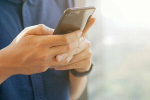 Close up businessman holding smartphone for checking work or make appointment and using application for manage job or surf the internet at outside office , technology lifestyle concept