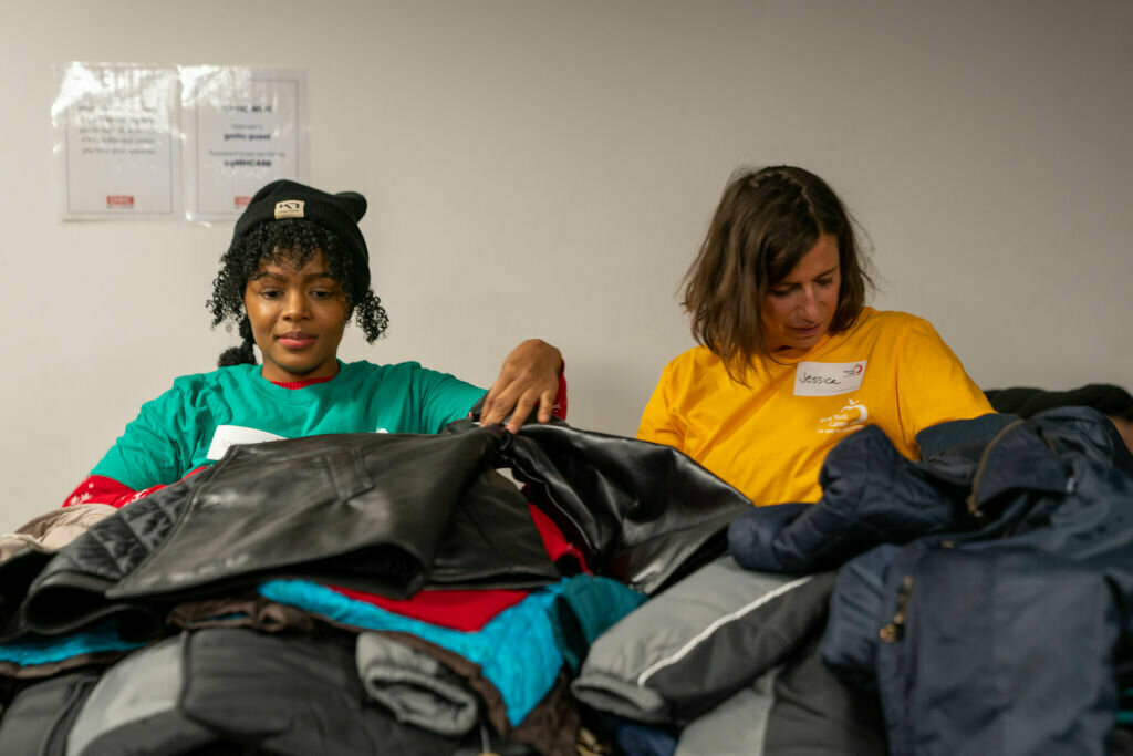 Volunteers of New York Cares sort through a table of coats that have been donated for people in need at the Gay Men's Health Crisis (GMHC) offices on Dec. 24, 2019 in New York City.