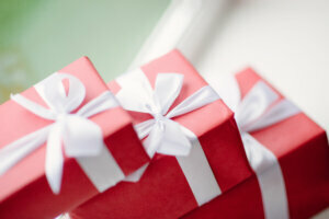 Red boxes of gifts tied with a white ribbon near the window
