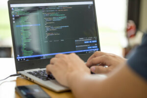 Freelance programmer or developer working at home and typing source code with laptop