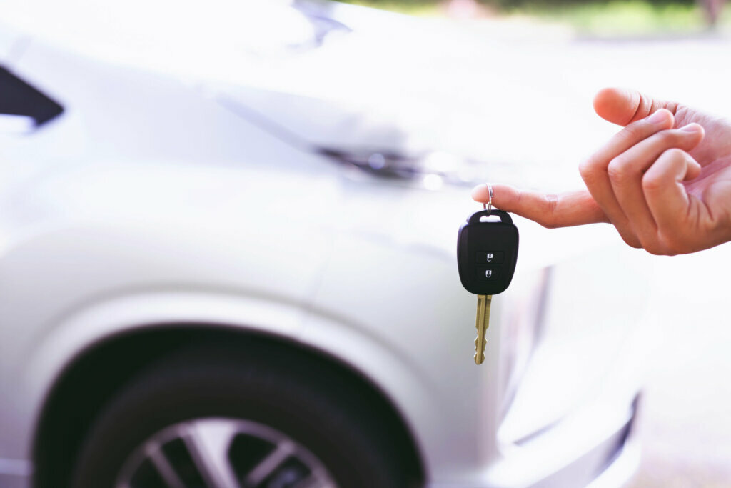The male salesman shows the new car keys to the customers in the showroom.