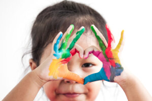 Cute asian child girl with hands painted make heart shape on white background