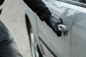 Car thief hand pulling the handle of a car