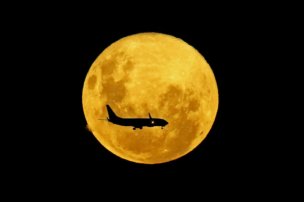 A plane passes in front of the full moon as seen from Curitiba, Brazil on March 9, 2020. - The supermoon is visible as the full moon coincides with the satellite in its closest approach to Earth, which makes it appear brighter and larger than other full moons.