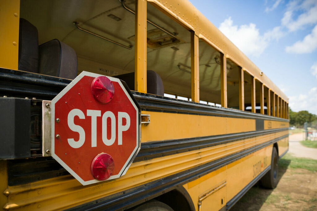 A red stop sign with lights on the side of an old yellow school bus. Back to school