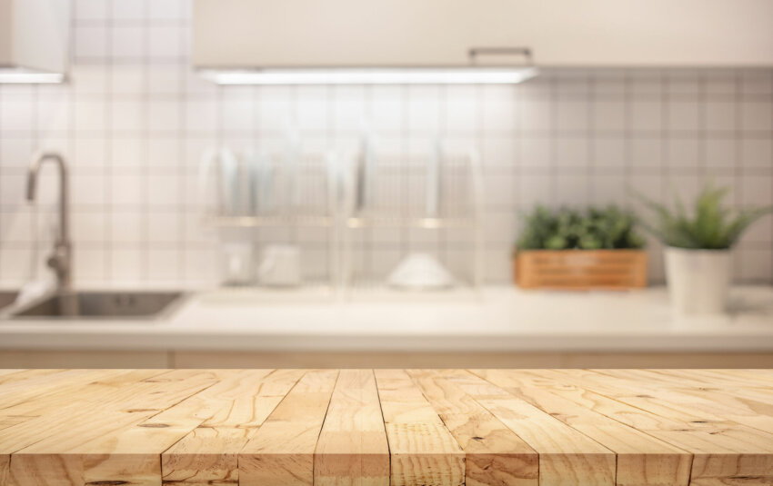 Wood table top on blur kitchen counter (room)background.