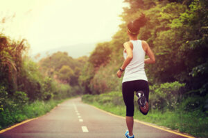 Young fitness woman runner running at forest trail