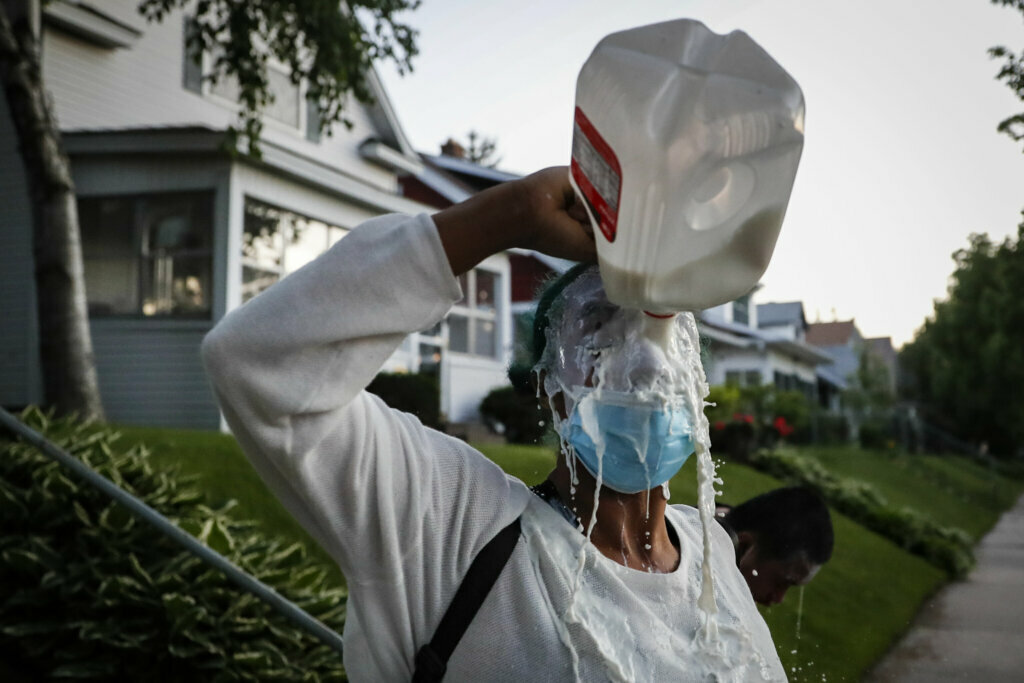 A protester douses her face with milk after being exposed to tear gas fired by police, Thursday, May 28, 2020, in St. Paul, Minn. Protests over the death of George Floyd, a black man who died in police custody Monday, broke out in Minneapolis for a third straight night. (AP Photo/John Minchillo)