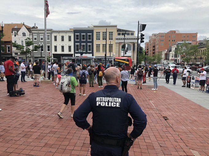 A police officer watches a crowd of demonstrators walk by May 29, 2020.