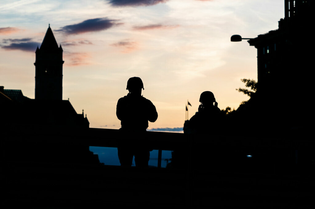 Members of the D.C. National Guard watch as protesters peacefully march down Pennsylvania Avenue on June 2, with the Trump International Hotel visible center left. After days of looting and clashes with police, protests thereafter remained largely peaceful, owing to a large security presence and a palpable effort among protesters to police their own. (WTOP/Alejandro Alvarez)