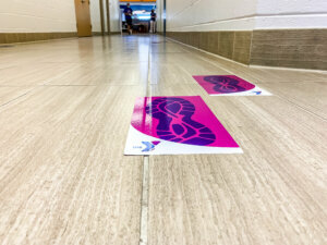 Markers on floors signify traffic circulation and distancing. The circulation pattern is one way in and one way out. Photo Albert Nimley