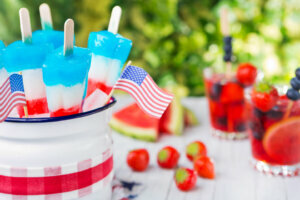 Red white and blue popsicles on an outdoor table with summer drinks