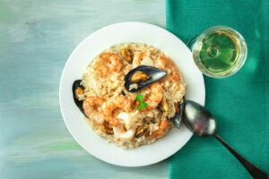 Seafood risotto plate on teal textures with copyspace