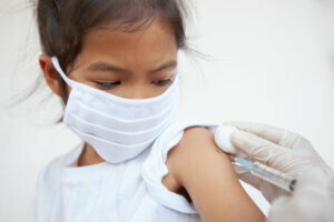 Doctor injecting vaccination on asian child girl arm. The child girl wearing protection mask for protect air smog pollution with PM 2.5 and Covid 19 virus