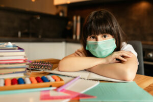 Portrait of girl with protective mask on face at home. Online learning concept
