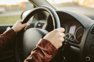 Close up of hands on car steering wheel at 10 and