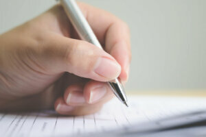 Hand of man signing signature filling in application form document business contract agreement