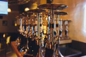 Group of eastern hookahs with black pipes on table in cafe. Shisha smoking concept.