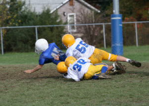 Four young football players tumble to the ground in a tackle