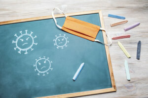Virus on a blackboard next to a protective mask
