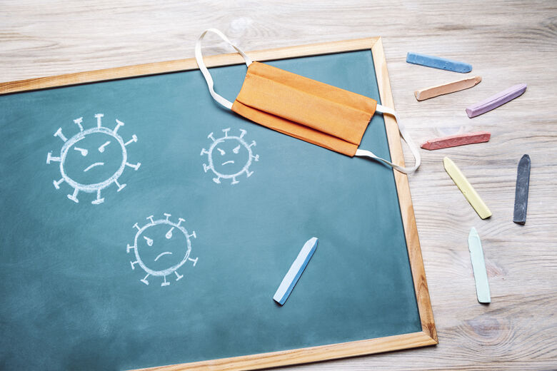 Virus on a blackboard next to a protective mask