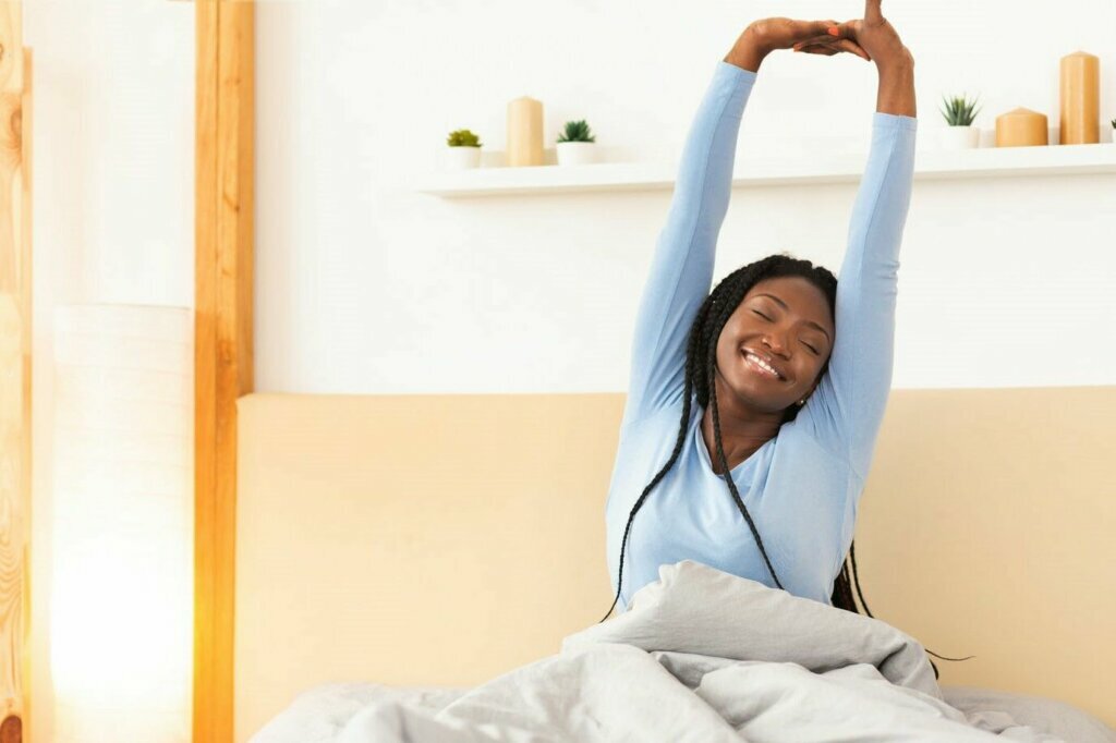 Rested African American Girl Waking Up Sitting In Cozy Bedroom