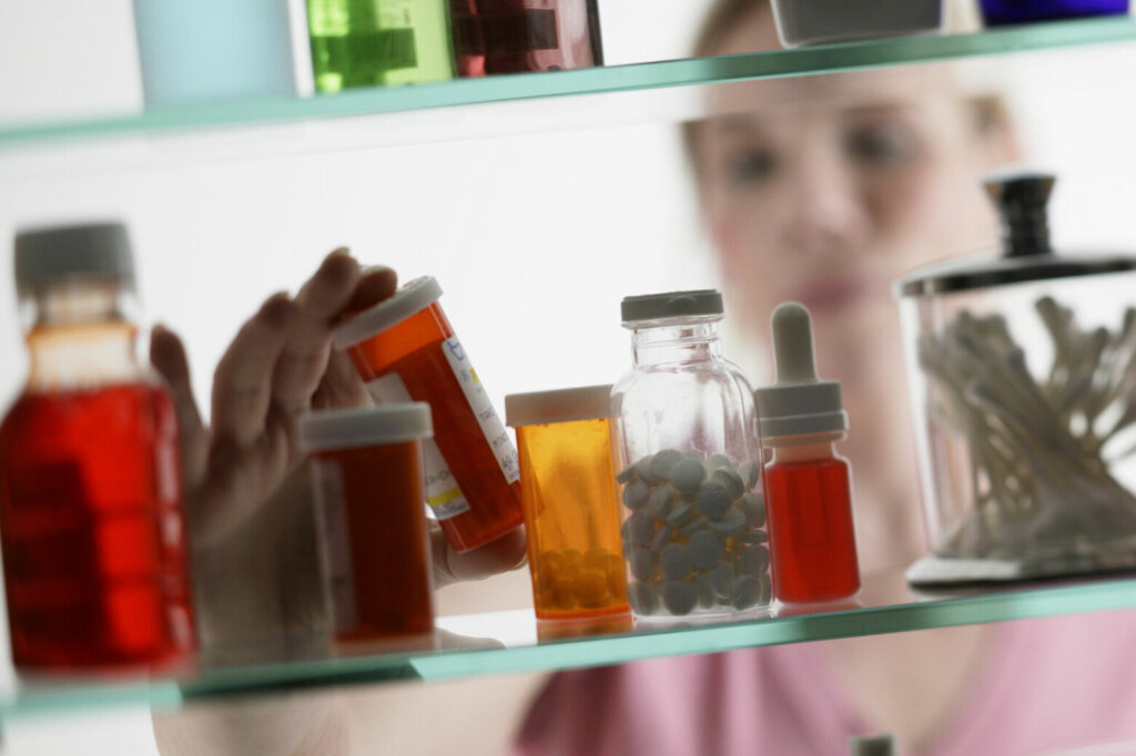 Woman taking pills from medicine cabinet