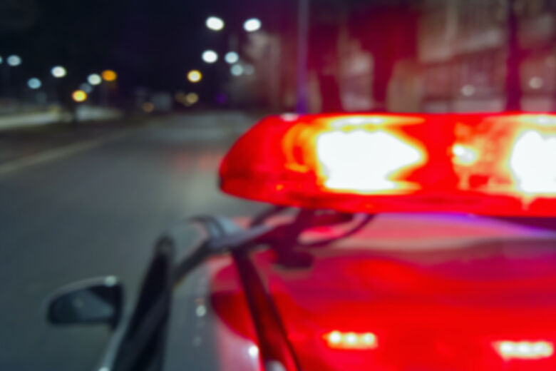 Police car red lights in night time, crime scene, night patrolling the city. Abstract blurry image.
