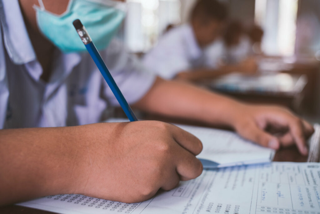 Students wearing mask for protect corona virus or covid 19 and doing exam in classroom with stress.