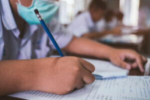 Students wearing mask for protect corona virus or covid 19 and doing exam in classroom with stress.