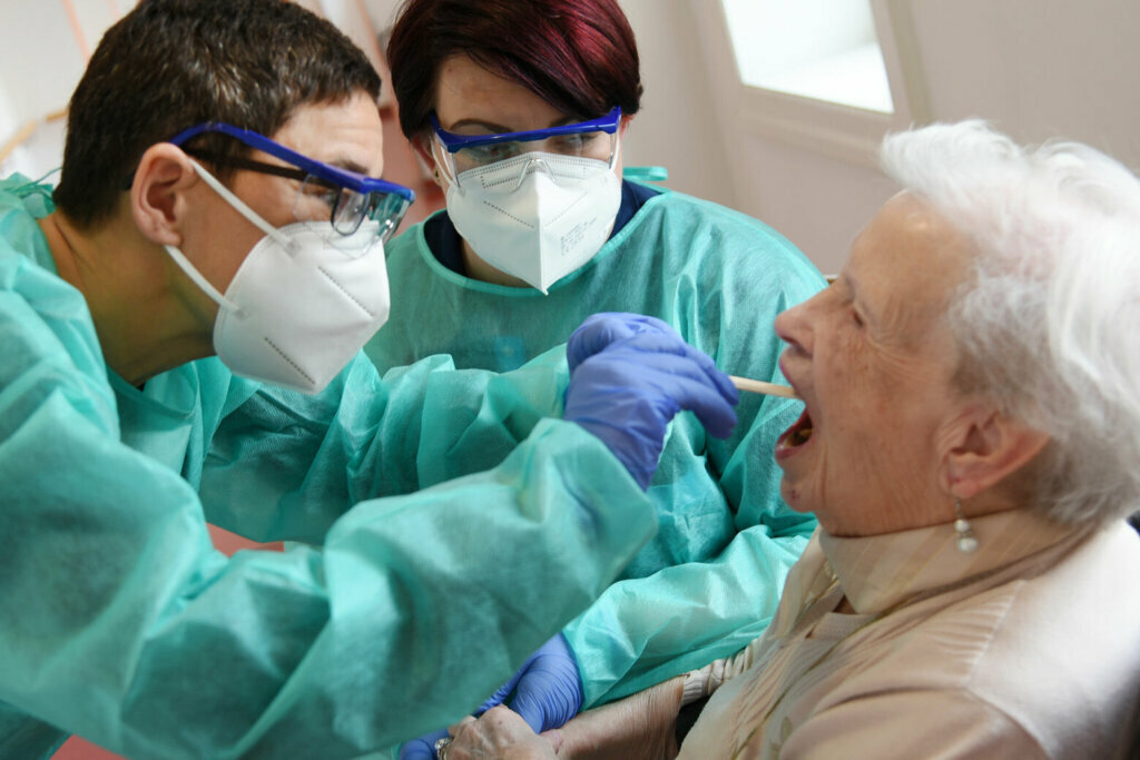 Nurses testing a elderly patient in a nursing home for the coronavirus.